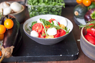 top view of ceramic bowl with tomato and cheese salad with herbs 