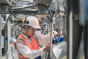 Engineers inspect gas and water pipes for power and cooling in industrial and building systems. workers in safety gear work seriously in oil and gas refining plant with pipes connecting to machinery.