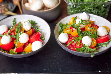 top view of ceramic bowl with tomato and cheese salad with herbs 