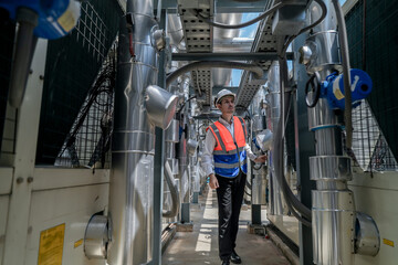 Engineers inspect gas and water pipes for power and cooling in industrial and building systems. workers in safety gear work seriously in oil and gas refining plant with pipes connecting to machinery.