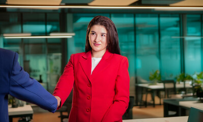 business concepts and closing business deals. businesswoman in red coat shakes hands with another...