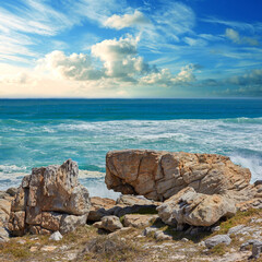 Rocks, ocean and water in nature outdoor for travel destination, coat environment and natural beauty. Blue sky, beach and scenery for seaside peace, tourism journey with adventure location of view