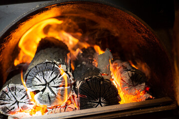Burning firewood in fire-box of boiler in country cottage.