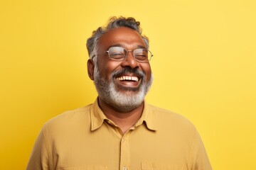 Obraz premium Portrait of a content indian man in his 50s wearing a comfy flannel shirt on pastel yellow background