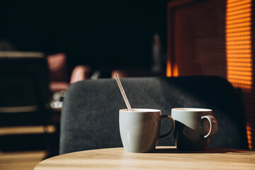 Two gray cups in the interior of a sunny cafe in the morning. Cups of tea on the table in a modern cafe. Cozy cafe with cups of coffee on the table. Meeting concept. Copy space.
