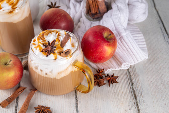 Apple pie spices latte drink, cosy autumn warm coffee beverage with apple pie syrup and spices, with fresh red apples, cinnamon, anise, copy space