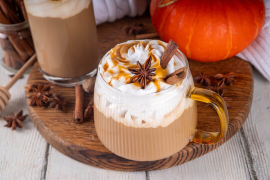 Pumpkin pie spices latte drink, cosy autumn warm coffee beverage with pumpkin pie syrup and spices, with fresh orange pumpkin, cinnamon, anise, copy space