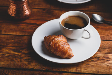 Cup of Black Coffee and Fresh Croissant on White Plate