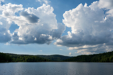 White puffy clouds and blue sky above Vlasina Lake. White cumulus clouds and a blue sky with sun rays. Beautiful semi-artificial lake in Southeast Serbia. 