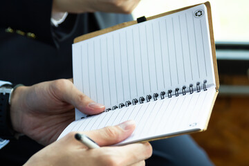 Closeup Businessman holding notebook in his hands while making important notes. Notebook in hands.