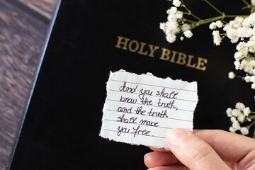 Hand holding Christian handwritten quote with God's words that His truth will make you free....
