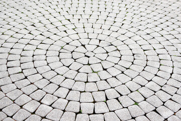 Background of paving slabs laid in circles, overgrown with grass