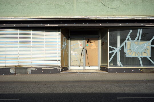 Leerstehendes Gesch&auml;ft mit alter Jalousie, Notverglasung und zersprungenem Schaufenster mit Klebeband bei Sonnenschein in der Krofdorfer Stra&szlig;e in Gie&szlig;en in Hessen