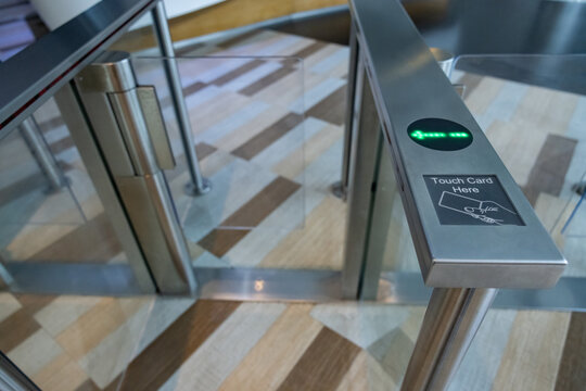 A metal gate with a green light on electronic turnstiles. - Powered by Adobe