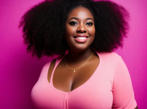 A curvy black woman posing in a photoshoot on a pink backdrop