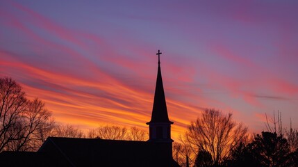 Obraz premium Sunset view with the silhouette of a church steeple, framed by a beautifully colored evening sky.