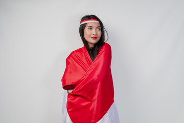 Young Asian woman with Indonesian flag draped over her shoulders and posing for a picture.