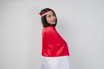 Young Asian woman with Indonesian flag draped over her shoulders and posing for a picture.