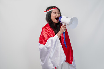 Energetic Asian woman with country flag draped over her shoulder while shouting at a megaphone.