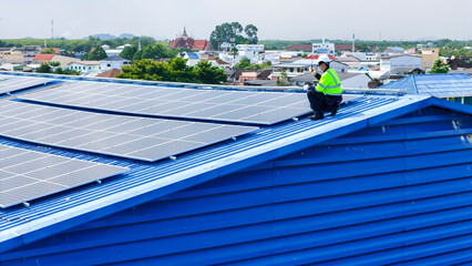 Naklejka premium engineer man inspects construction of solar cell panel or photovoltaic cell by electronic device. Industrial Renewable energy of green power. factory worker working on tower roof.