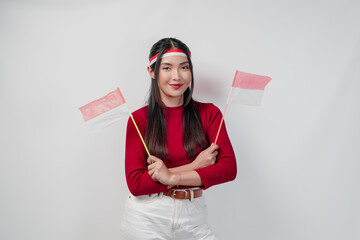 A happy young Asian woman is holding two mini Indonesian flags and smiling.
