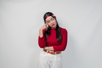 Thoughtful young Asian woman in a red shirt and white pants is confused and think of something.