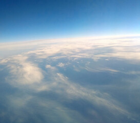 Vast horizon with soft clouds under bright blue sky during daytime flight above earth