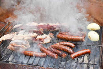 Sausages on a smoking grill, close-up. Sausage BBQ on wood ember, smoking. Barbecue, smoke background