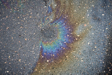 Surface of multi-colored fuel stains on wet asphalt
