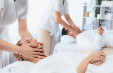 Fototapeta premium Caucasian couple enjoying relaxing anti-stress head massage and pampering facial beauty skin recreation leisure in dayspa modern light ambient at luxury resort or hotel spa salon. Quiescent