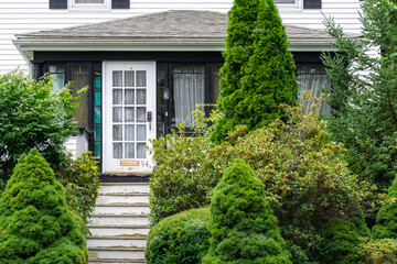 Old house entrance facade surrounded by lush greenery in Brighton, Massachusetts, USA