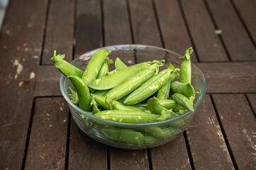 Fresh green peas in a glass bowl on a wooden table