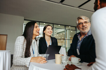 Coworkers chatting at a conference table, discussing ideas and networking in a modern office environment