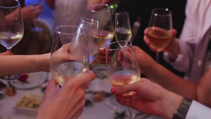 Group of guests celebrate and raise glasses, cheering with alcohol glasses with wine and champagne in the restaurant on corporate christmas birthday party event or wedding celebration, luxury event