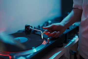 Close-up of a DJ's hand on a turntable, setting up for a music session.