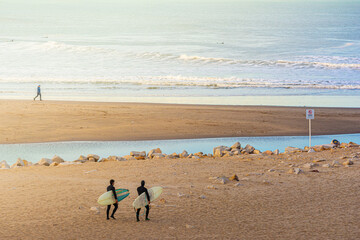 surfistas caminando hacia el mar en un dia calido con olas 