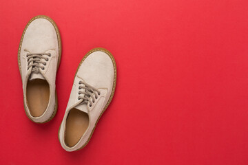 Beige suede shoes on color background, top view