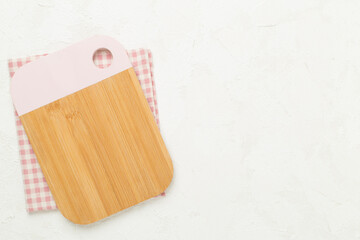 Cutting board with napkin on concrete background, top view