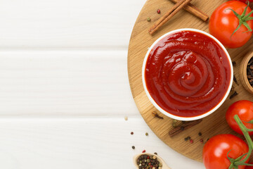 Delicious ketchup with spices and tomatoes on wooden background, top view