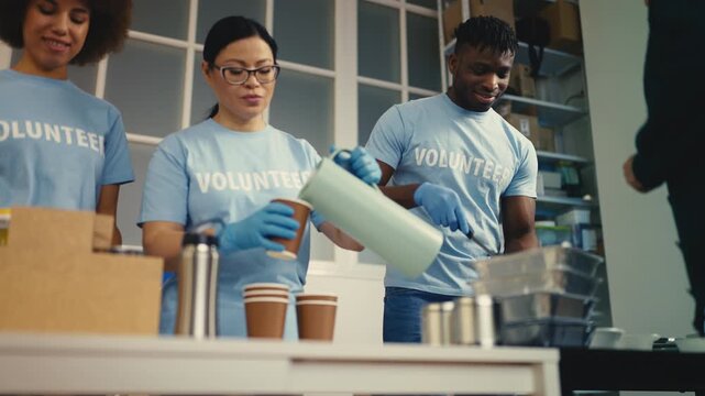 Multiethnic volunteers working at soup kitchen, feeding the hungry people