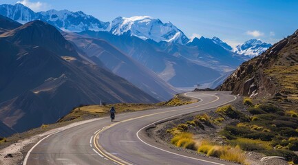 Winding mountain road ina Valley, California with snow-capped mountains and golden rocks on the sides. mountain range with snow capped mountains in the distance and a cloudy sky.