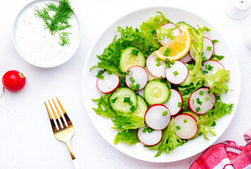 Summer vegan crispy salad with cucumbers, radishes and lettuce, white background, top view