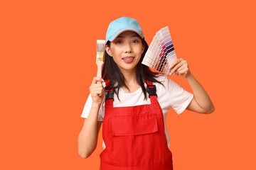 Female Asian painter with paint color palettes and brush on orange background