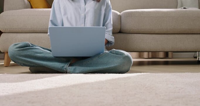 A Modern Home Scene: Woman Types on Laptop as Robot Vacuum Delivers Tea for a Cozy, Tech-Savvy Moment