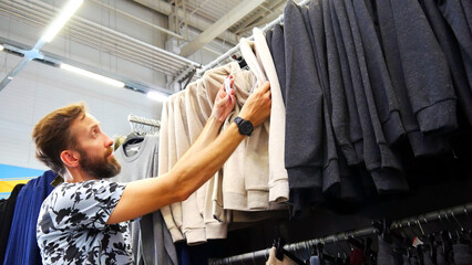 A male buyer choosing a hoodie in a clothing store