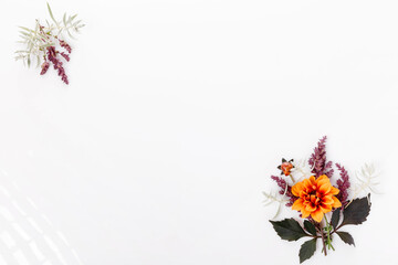 Floral autumn composition of orange dahlia flowers and green leaves on white background. Wedding concept. Flat lay, top view