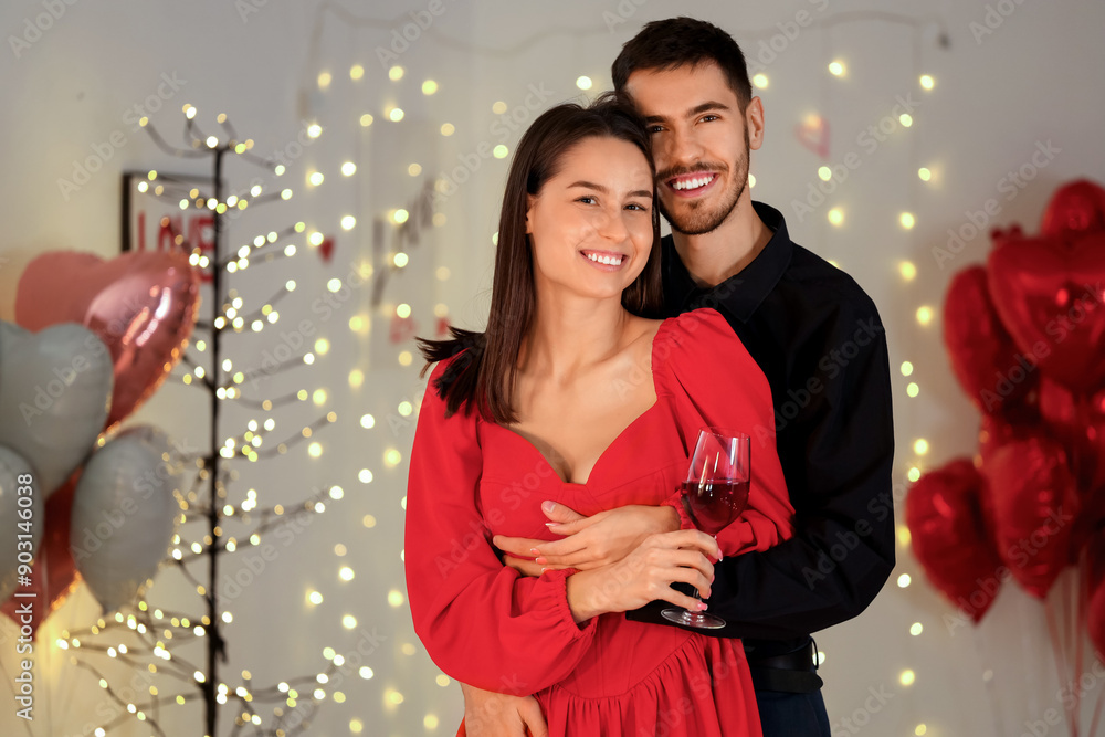 Wall mural Young couple with glass of wine hugging at home on Valentine's Day