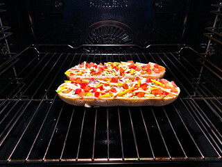 Baguettes with cheese and peppers in the oven.