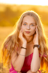 Fototapeta premium A beautiful Ukrainian girl on a wheat field in the rays of the sun