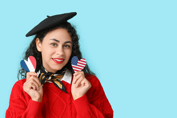 Beautiful young happy African-American woman with USA and France flags in shape of hearts on blue...